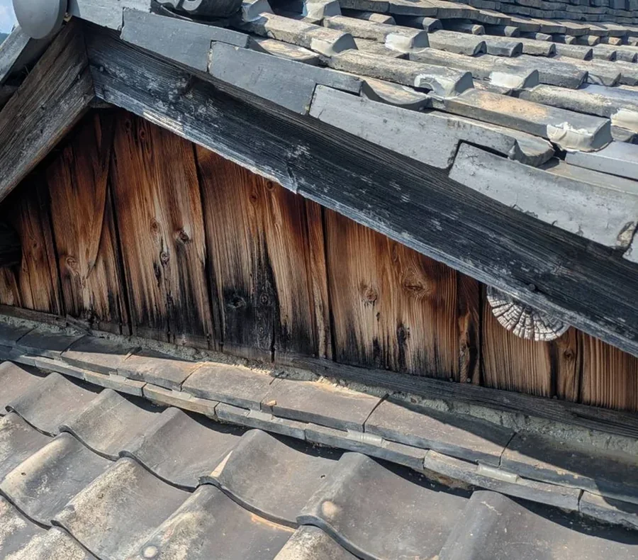 施工前の入母屋破風。木部が下へいくほど黒く、縦筋状に変色している状態